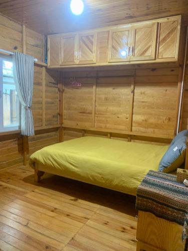 a bed in a room with wooden walls and wooden floors at Homestay Đồi Sương Trắng in Da Lat