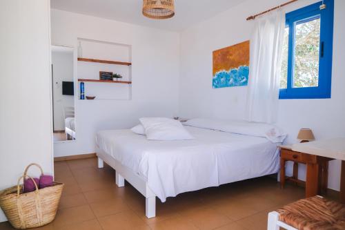 a white bedroom with a bed and a desk at VIVIENDAS ES CARNATGE in Playa Migjorn