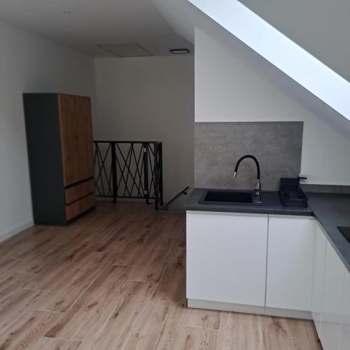 a kitchen with white cabinets and a sink in a room at Apartamenty Zagórze 55 in Zagórze