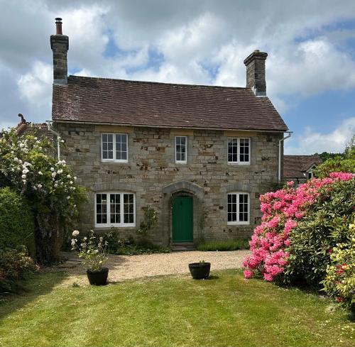 a brick house with a green door and pink flowers at Detach Sandstone Cottage, Sleeps 6, 2 x King Size, 2 x Singles in Lower Beeding