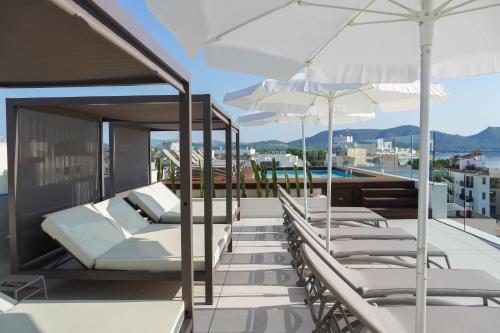 a balcony with white lounge chairs and umbrellas at Marins Naiya Boutique Hotel in Cala Bona