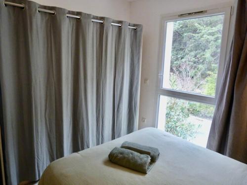 a bed with a towel on it in front of a window at Le Clos d'AIX Studio 113 in Aix-en-Provence
