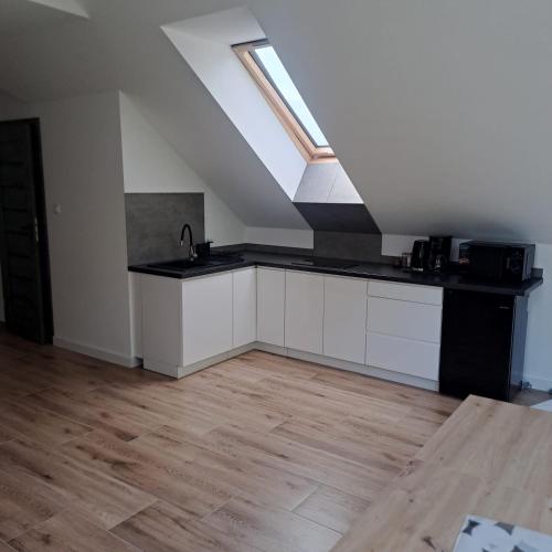 a kitchen with white cabinets and a skylight at Apartamenty Zagórze 55 in Zagórze