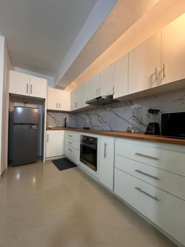 a kitchen with white cabinets and a stainless steel refrigerator at Cómodo Apartamento vacacional in Porlamar