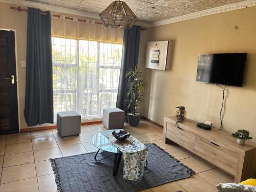 a living room with a table and a tv on the wall at Guesthouse at 543 in Lebowakgomo