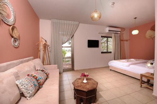 a living room with a couch and a bed at Almog Hotel in Almog