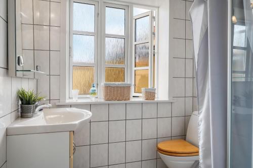 a white bathroom with a toilet and a sink at Charming Townhouse From 1877, Located In The Middle Of Løgstør Only 100 Meters From The Harbor in Løgstør