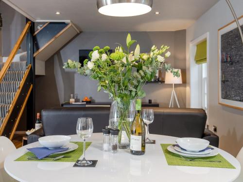 a table with a vase of flowers and wine glasses at Granary in Gatehouse of Fleet