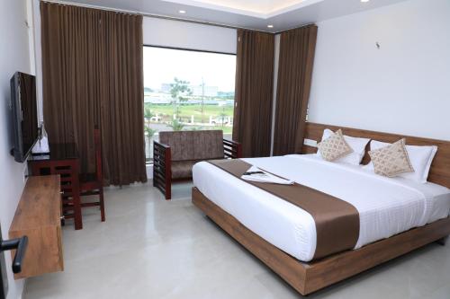 a bedroom with a bed and a desk and a television at Aura Airport Hotel in Nedumbassery
