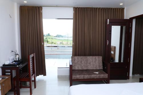 a bedroom with a bed and a chair and a window at Aura Airport Hotel in Nedumbassery