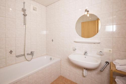 a bathroom with a sink and a tub and a mirror at Appartements Huber in Fügen