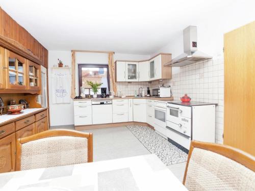 a kitchen with white cabinets and a table with chairs at Wohnung in Densberg nahe Kellerwald in Densberg
