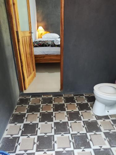 a bathroom with a toilet and a bedroom with a bed at Radeva 2 menjangan villa in Banyuwedang