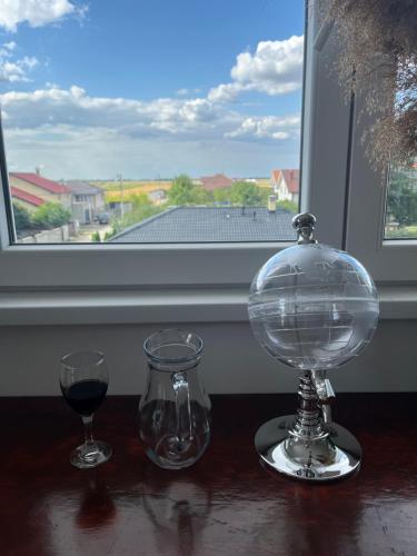 two glasses and a glass bowl on a table with a window at Airport Art Villa in Surčin