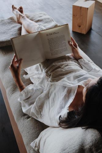 a woman laying in bed reading a book at La Butte in Plouider