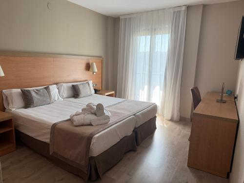 a bedroom with a bed with two stuffed animals on it at Hotel Real in Lleida