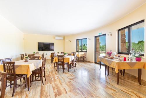 Un comedor con mesas y sillas y ventanas. en Agriturismo Cutura, en Parabita