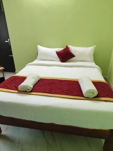 a large bed with red and white sheets and pillows at Rajeshwari Tower & Residency in Tiruvannāmalai