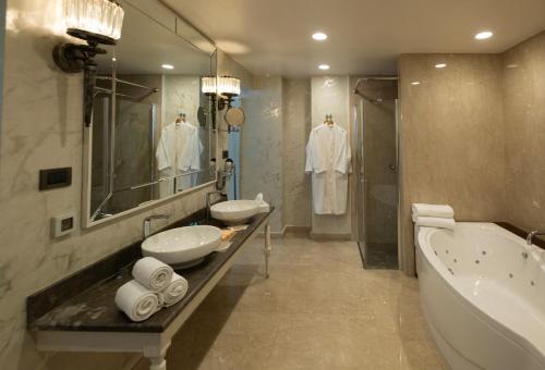 a bathroom with two sinks and a bath tub and a tubermott at Ramada Plaza by Wyndham Mardin in Mardin