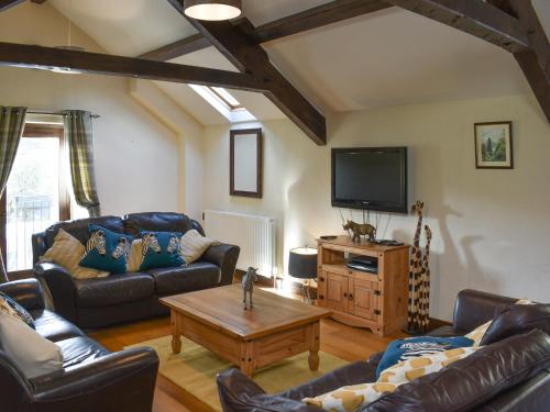 een woonkamer met leren banken en een tv bij Combe Cottage-Uk42228 in Low Borrowbridge