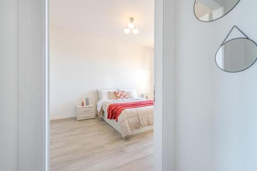 a white bedroom with a bed and a mirror at The Purple House between Modena and the Ferrari Museum in Modena