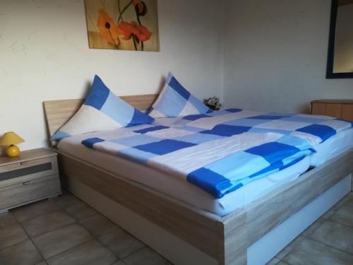 un letto con lenzuola e cuscini blu e bianchi di Wohnung in Silbecke mit Pool und Wald ad Attendorn