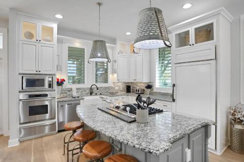 a kitchen with white cabinets and a island with bar stools at A Better Place in Carillon Beach