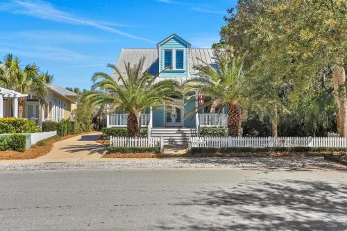 a blue house with palm trees and a white fence at A Better Place in Carillon Beach