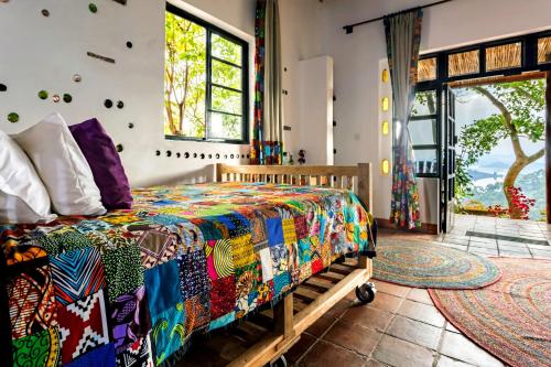 a bedroom with a bed with a colorful quilt at Chameleon Hill Forest Lodge in Bwindi