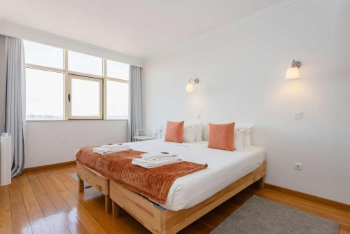 a bedroom with a bed with white sheets and orange pillows at Liiiving in Gaia - Douro Balcony View in Vila Nova de Gaia
