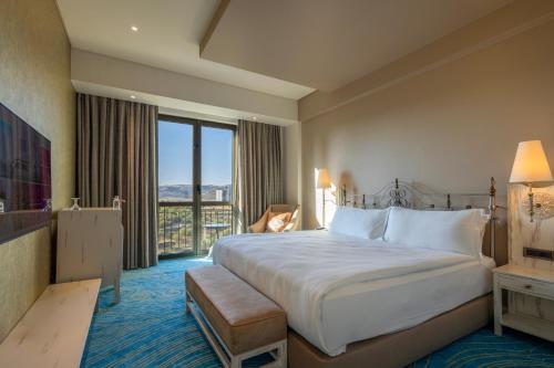 a hotel room with a bed and a large window at Ramada Plaza by Wyndham Mardin in Mardin