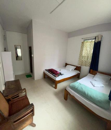 a bedroom with two beds and a chair at Hams Cherrapunji in Cherrapunji