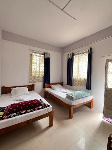 a bedroom with two beds and two windows at Hams Cherrapunji in Cherrapunji