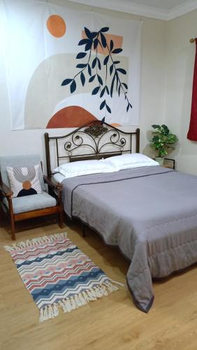 a bedroom with two beds and a chair and a painting at The Maple Homestay @ Kota Laksamana Melaka in Melaka