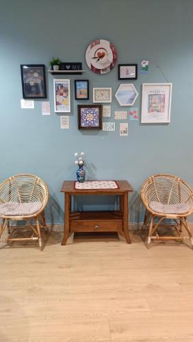 a table and two chairs and a wall with pictures at The Maple Homestay @ Kota Laksamana Melaka in Melaka