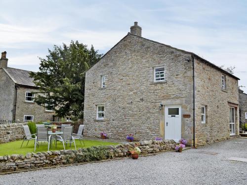 an old stone house with a table and chairs at The Granary in Carperby