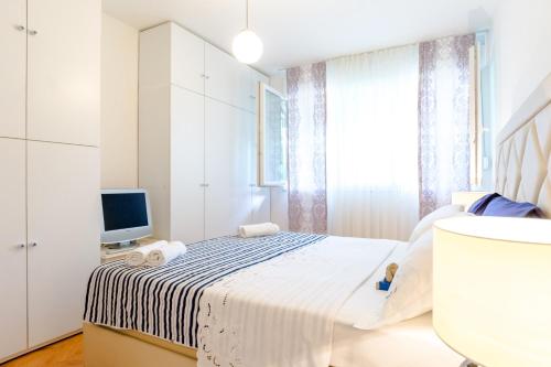 biała sypialnia z łóżkiem i telewizorem w obiekcie Apartment Mandalina w Splicie