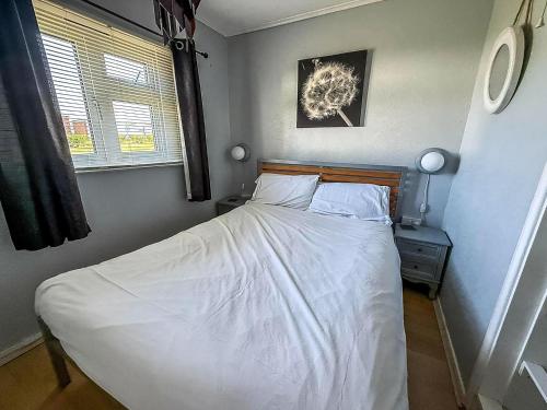 a bedroom with a bed with white sheets and a window at Modern 4 Berth Chalet At California Sands Near Scratby Beach Ref 52064Cs in Scratby