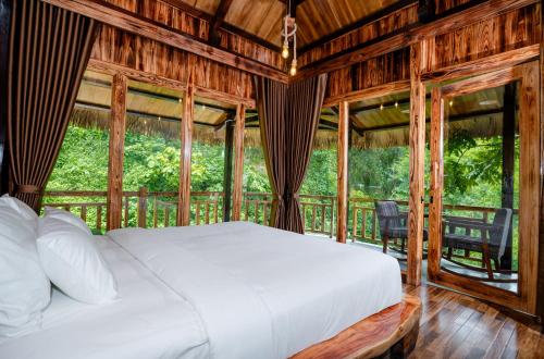 a bedroom with a bed in a room with windows at Asia Tropical Resort and Spa in Làng Coc