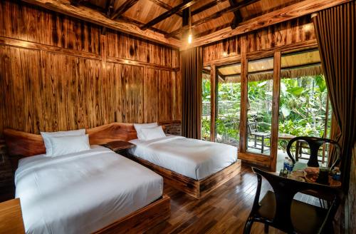 two beds in a room with wooden walls and windows at Asia Tropical Resort and Spa in Làng Coc