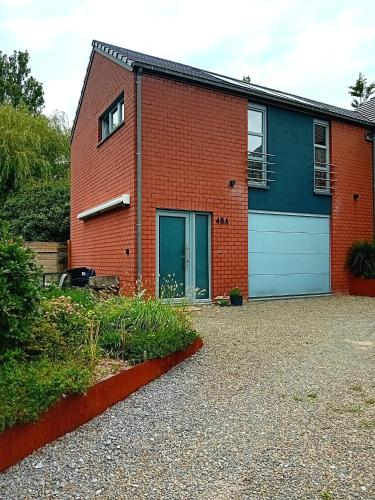 a red brick house with a blue garage at Le coin des évasions in Verviers