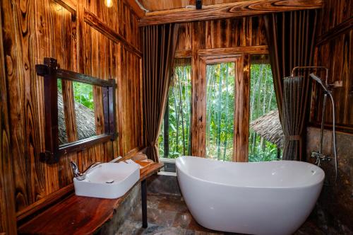 a bathroom with a white tub and a sink at Asia Tropical Resort and Spa in Làng Coc