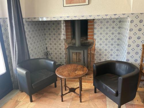 a living room with two chairs and a table and a fireplace at Shared Quinta with Pool and Olive Grove Views in Montemor-o-Novo