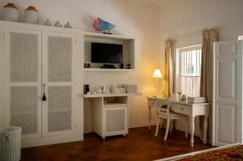 a room with a desk and a table with a television at Nyne Hotels Rock Villa - Bentota in Bentota