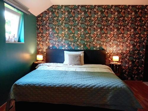 a bedroom with a bed with a floral accent wall at Le coin des évasions in Verviers