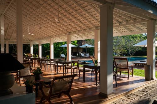 a covered patio with tables and chairs and a pool at Nyne Hotels Rock Villa - Bentota in Bentota