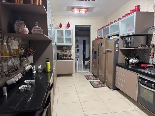 a kitchen with black counter tops and stainless steel appliances at COP 30 Casa com 04 Suítes e 01 Quarto individualizados in Belém