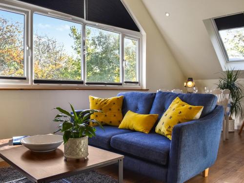 a blue couch with yellow pillows in a living room at Garden Studio in St Austell