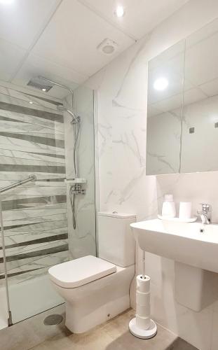 a white bathroom with a toilet and a sink at Blue Beach Apartment in Ifach