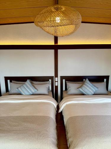 two beds in a room with a chandelier at 鴨川シーサイドヴィラ in Kamogawa
